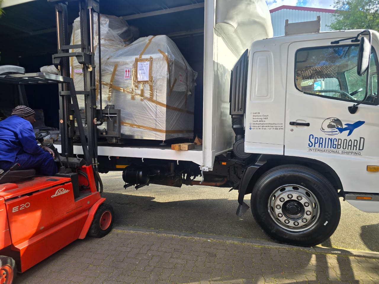 Imported crated cargo being loaded by forklift onto a Springboard truck